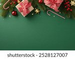 Top view of Christmas decorations with gifts, candy canes, and ornaments on a green background creating a festive holiday atmosphere