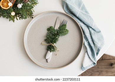 Top view of Christmas or New Year table setting with ceramic plate, fir branch with decor and cutlery. copy space