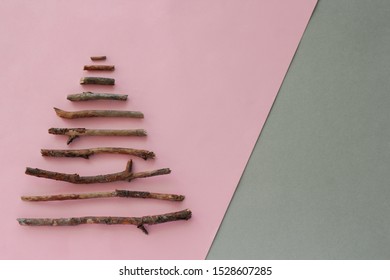 top view christmas tree silhouette  made from wooden twigs and  on a pastel pink and gray background with copy space