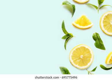 レトロなミントパステルの背景に柑橘類のスライスとミントハーブのフレーム、コピー用スペース。フルーツのコンセプトデザインが最小限。の写真素材