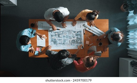 Top view of civil engineer team holding blueprint and standing at table with laptop, project plan and blueprint. Aerial view of skilled project manager planning and writing on sticky notes. Symposium. - Powered by Shutterstock