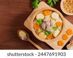 Top view of Clear soup with tofu and minced pork in wooden bowl on wooden table background. Asian Food