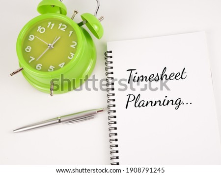 Top view of clock, pen and notebook written 