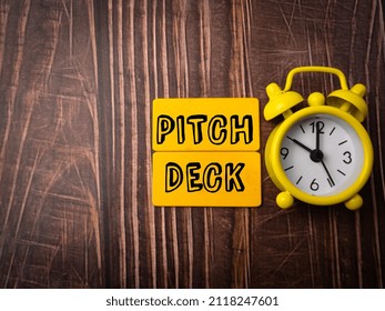 Top View Clock And Wooden Board With Text PITCH DECK On Wooden Background