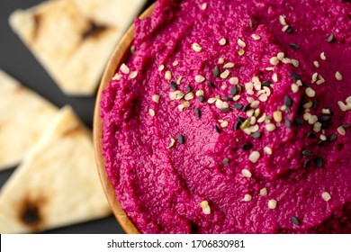 Top view and close up of a colorful beetroot hummus with pita on a black background 