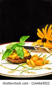 Top View, Close Distance Of An Autumn Dinner Of Portabella Mushroom Cap Filled With Freshly Roasted Maine Lobster With A Sprig Of Freshly Picked Basil On A White Plate With A Flower