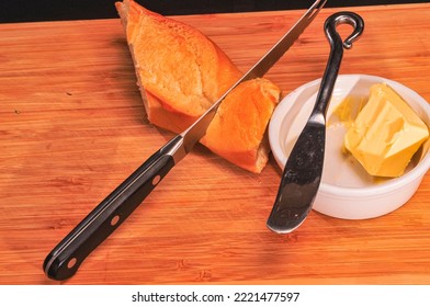 Top View, Close Distance Of A Knife In A French Baguette And White Ramekin With Butter And Knife