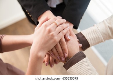 Top view close up of group showing unity putting hands together, linked by interest in a common cause, three entrepreneurs starting own small business, joint ventures, launching startup, team building