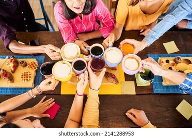 Top view of close up hands of Multicultural People having breakfast drinking coffee and cheers. Happy community fun together in a terrace bar. - Powered by Shutterstock