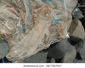 Top view close up of old tangled fishing nets and ropes piled on coastal rocks