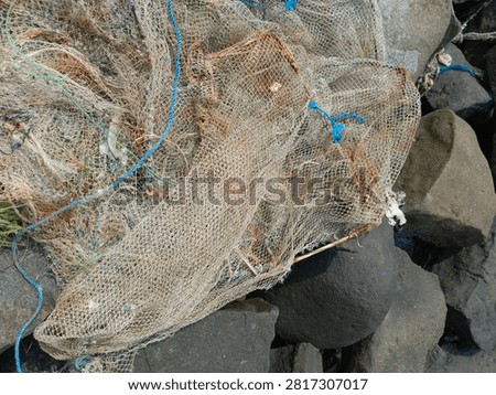 Top view close up of old tangled fishing nets and ropes piled on coastal rocks