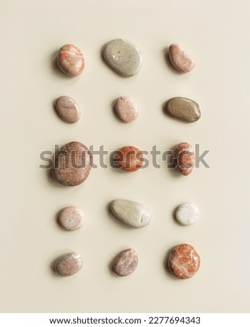 Top view close up pebbles sea stones on sand color background. Square composition from natural stone natural tones. Minimal style flat lay, concept of calm, peace, meditation. Creative summer pattern.