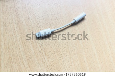 Top view and close up photo of a white lightning to 3.5mm headphone jack audio adapter cable for smart phone on work desk from home.