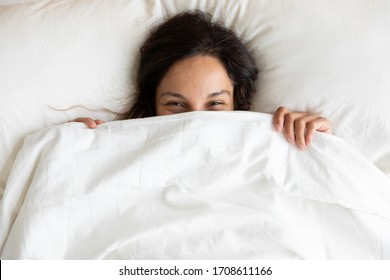 Top View Close Up Playful Pretty Girl Hiding Face, Peeking From Blanket, Lying On Soft Pillow In Bed, Looking At Camera, Beautiful Young Woman Shy, Covering Face With Duvet, Having Fun At Home