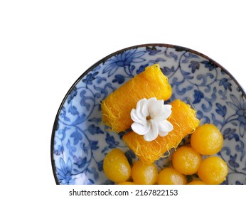 Top view, Close up of Thai style Fios de ovos, rolled golden egg yolk thread and gold egg-yolks drops, Thong yot, traditional sweet food dessert in blue painting plate, copy space with clipping path