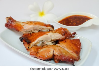 Top view and close up: Juicy grilled chicken wing on white plate and spicy Thai style sauce isolated on white background. Recommend menu with papaya salad (SOM TUM) famous and popular food.