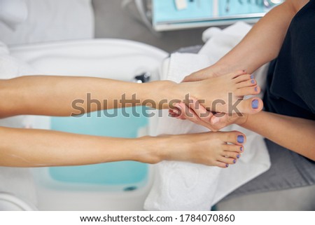 Top view close up of woman feet enjoying massage after pedicure by professional in spa salon