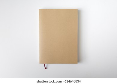 Top View Of Closed Blank Craft Brown Paper Cover Notebook On White Desk Background