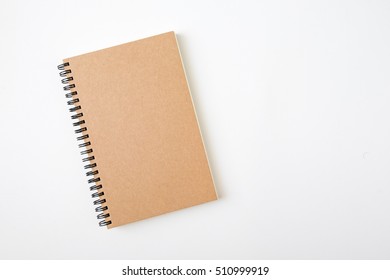 Top View Of Closed Spiral Blank Recycled Paper Cover Notebook On White Desk Background