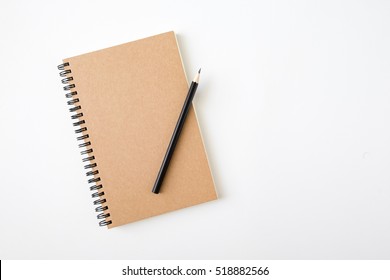 Top View Of Closed Spiral Blank Craft Paper Cover Notebook With Pencil On White Desk Background