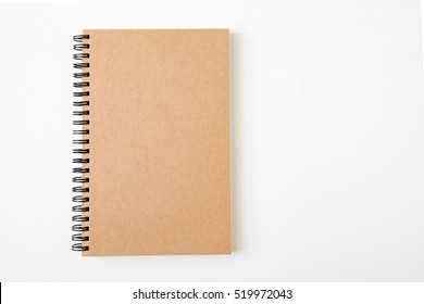 Top View Of Closed Spiral Blank Recycled Paper Cover Notebook On White Desk Background