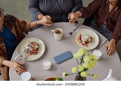 Top view closeup of African American family sitting at dining table and holding hands in prayer copy space - Powered by Shutterstock