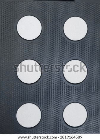 Top view close-up of a black plastic folding step stool top surface with anti-slip dot texture and circular holes.