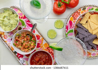 Top View Closeup Of Chips And Salsas And Margaritas On White Wood Background