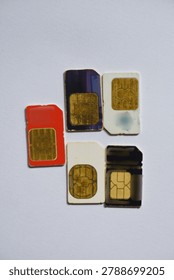 Top view close-up of different SIM card formats arranged on white textured surface, useful for concepts of mobile communication and digital connectivity.