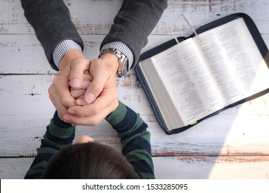 Top View Closeup Of A Father And His Little Son's Hands Praying Together After Bible Study In The Morning. Christianity, Parenting And Raising Child In God's Way, Thankful Moment, Happy Father's Day.