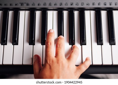 top view, close-up of a female hand playing the keys of an electronic synthesizer.