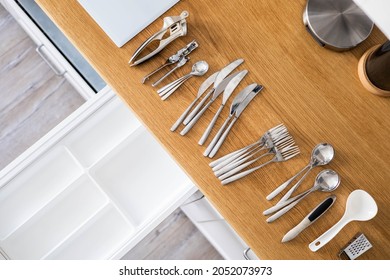 Top view closeup housewife hands tidying up cutlery in drawer general cleaning at kitchen. Woman neatly assembling fork, spoon, knife accessories for eating use Konmari storage organization method - Powered by Shutterstock