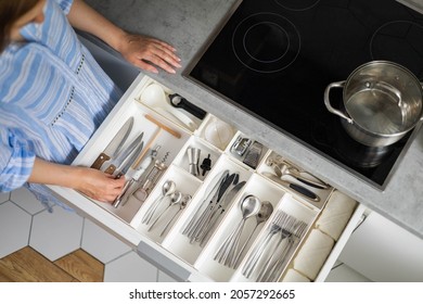 Top view closeup housewife hands tidying up cutlery in drawer general cleaning at kitchen. Woman neatly assembling fork, spoon, knife accessories for eating use Konmari storage organization method - Powered by Shutterstock