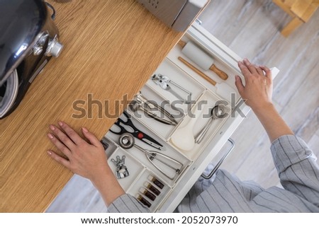 Top view closeup housewife hands tidying up cutlery in drawer general cleaning at kitchen. Woman neatly assembling fork, spoon, knife accessories for eating use Konmari storage organization method