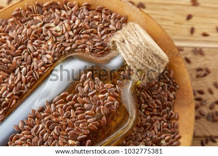 Top view closeup picture flax seeds and linseed oil in a glass bottle on a wooden background, shallow depth of field.