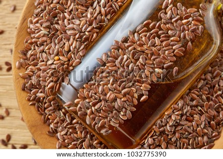 Top view closeup picture flax seeds and linseed oil in a glass bottle on a wooden background, shallow depth of field.