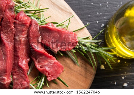 top view closeup of a raw italian tagliata, beaf steak., on a wooden chopboard with rosemary, salt and olive oil Stock photo © 