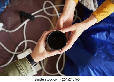 Top View Closeup Of Refugees Sharing Cup Of Hot Tea While Hiding In Shelter Together During War Or Crisis, Copy Space