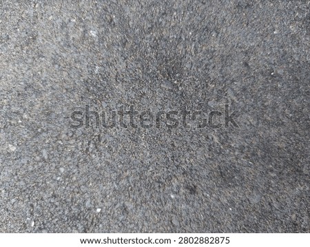 Top view close-up of a rough dark grey asphalt pavement texture background.