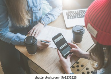 Top view, close-up smartphone in female hands. Meeting of two friends in cafe.Girls learn online, drinking coffee. First woman takes notes,and second uses a smartphone.Freelancers work outside office. - Powered by Shutterstock