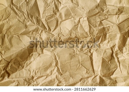 Top view close-up texture of crumpled brown kraft paper featuring sharp creases, dense wrinkles, and organic shadows, ideal for vintage backgrounds, eco-friendly branding, recycling concepts, and rustic design backdrops.