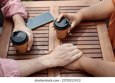 Top view closeup of two senior people holding hands while enjoying romantic date at outdoor cafe - Powered by Shutterstock