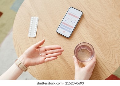 Top View Closeup Of Unrecognizable Woman Taking Birth Control Pills With Glass Of Water