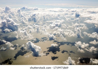 Top view of clouds floating over the sea in the setting sun. Golden reflections on the water.