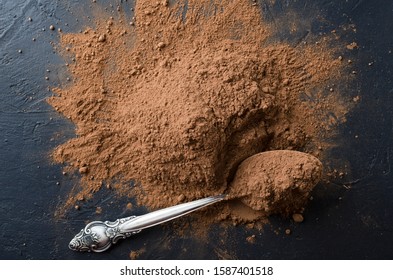 Top View Of Coca Powder And Metal Spoon On The Dark Kitchen Table