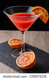 Top View Of Cocktail Glass With Blood Orange Martini, Half Orange, On Black Slate And Wood, Vertical