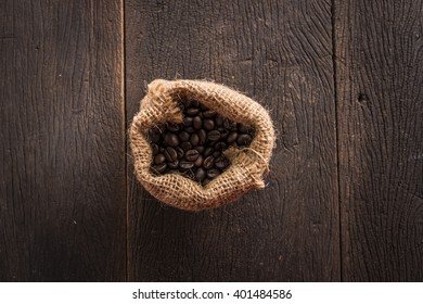 Top View Coffee Bean In Sackcloth Bag On Wood Table.