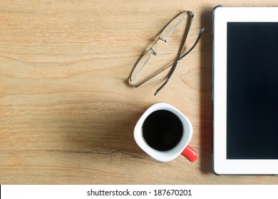 Top view of coffee cup , glasses and tablet on wooden table with space