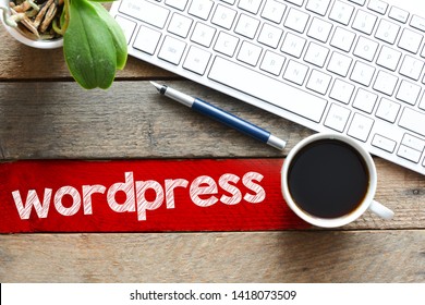 vista superior de la taza de café y el teclado con inscripción de WordPress en la mesa