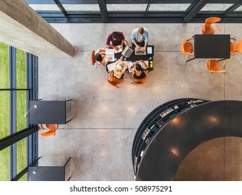 Top View Of College Students Sitting In A Library With Books And Laptop. Young People Studying Together At Public Library.